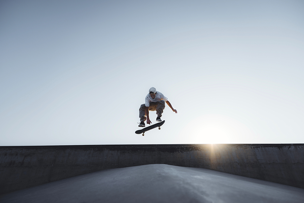 Skater doing kickflip on the ramp at skate park - Stylish skaterboy training outside - Extreme sport life style concept