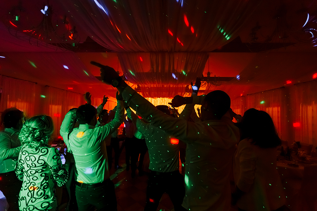 Portrait of newlywed couple and their friends in banquet hall. Wedding party. Groomsmen having fun and dancing at wedding banquet. Selective focus.