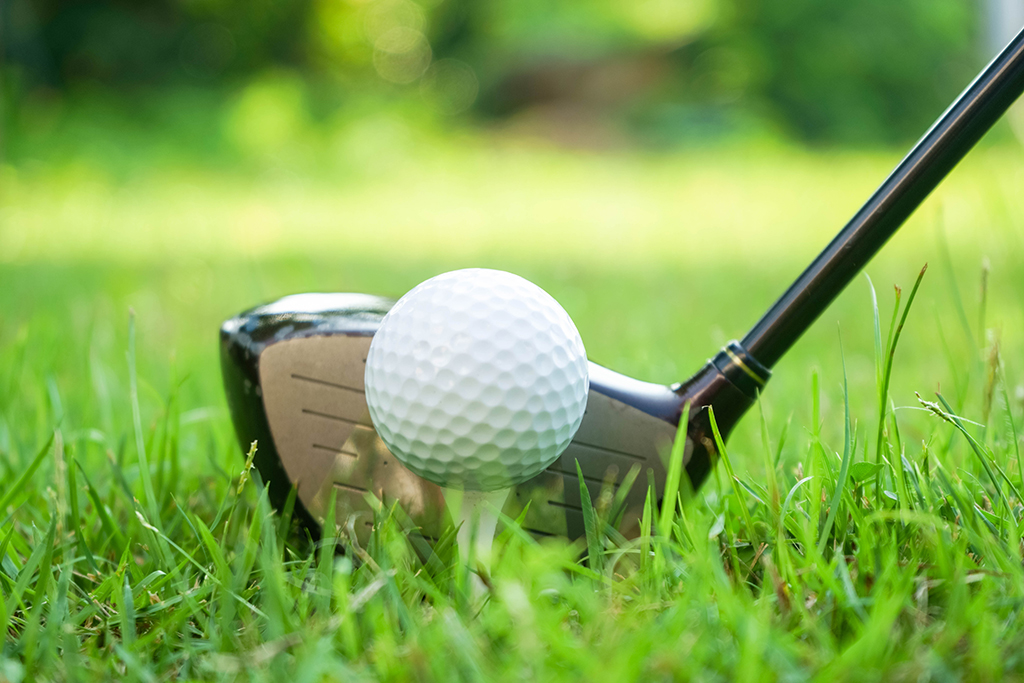 Golf ball and golf club in beautiful golf course at sunset background.