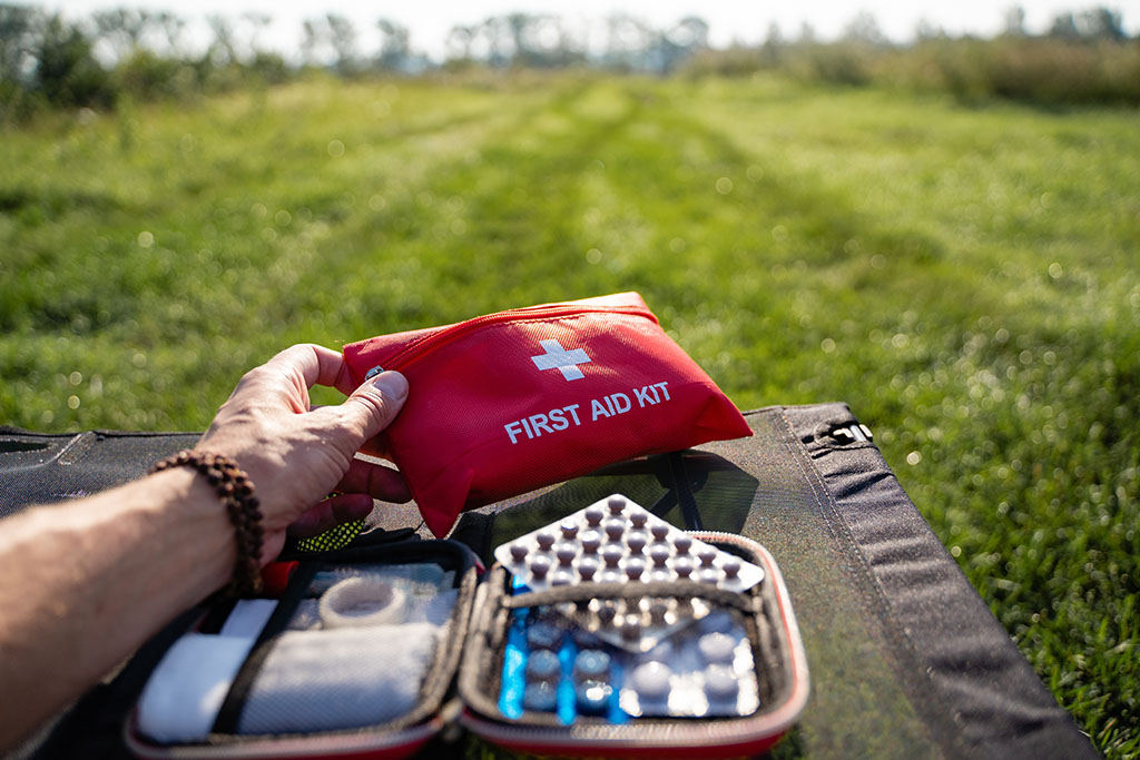 someone sitting in a field looking through the contents of a well-stocked first aid kit.