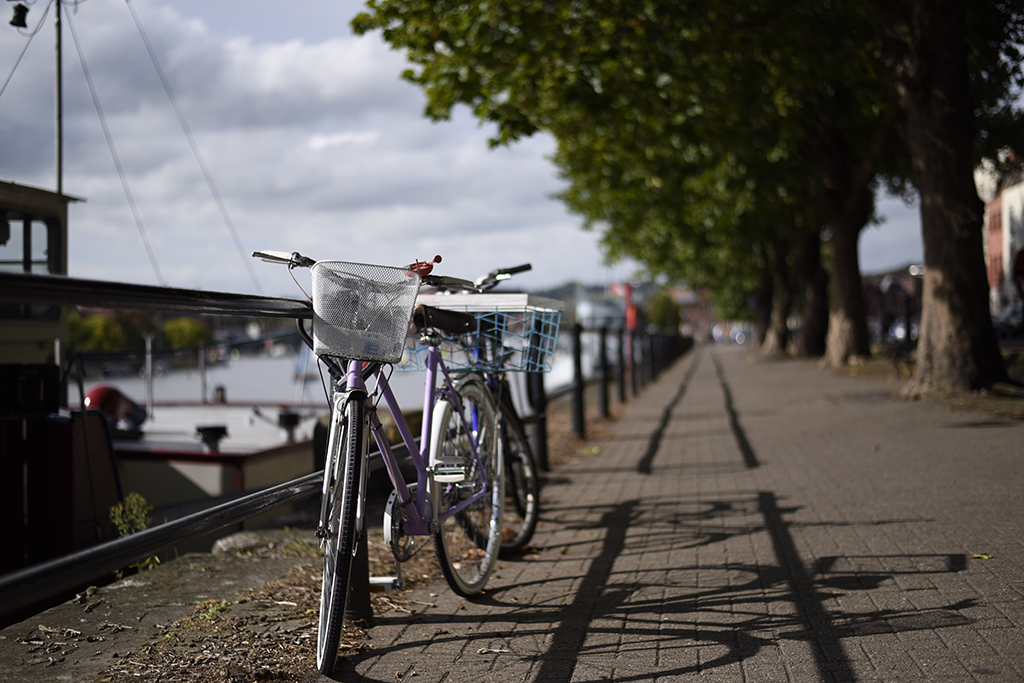 Two city woman bikes parked on pathway on riverside at bristol, UK. Bright lady bicycles vintage style with baskets in summer sunny town. Elegant recreational vehicles