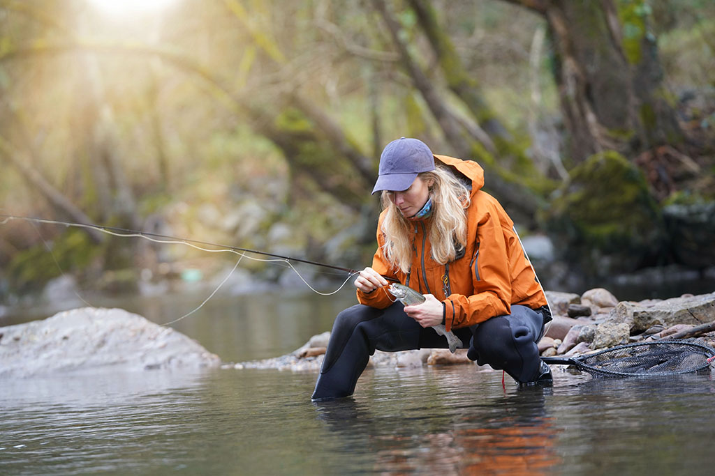 woman fly fishing catching rainbow trout