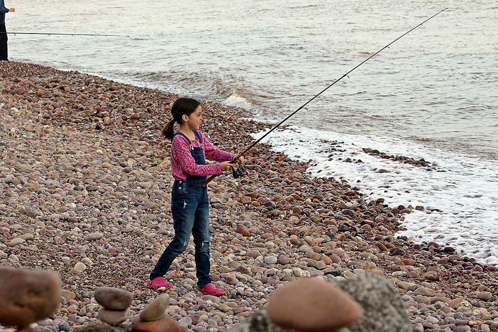 a young girl fishing on Sidmouth beach