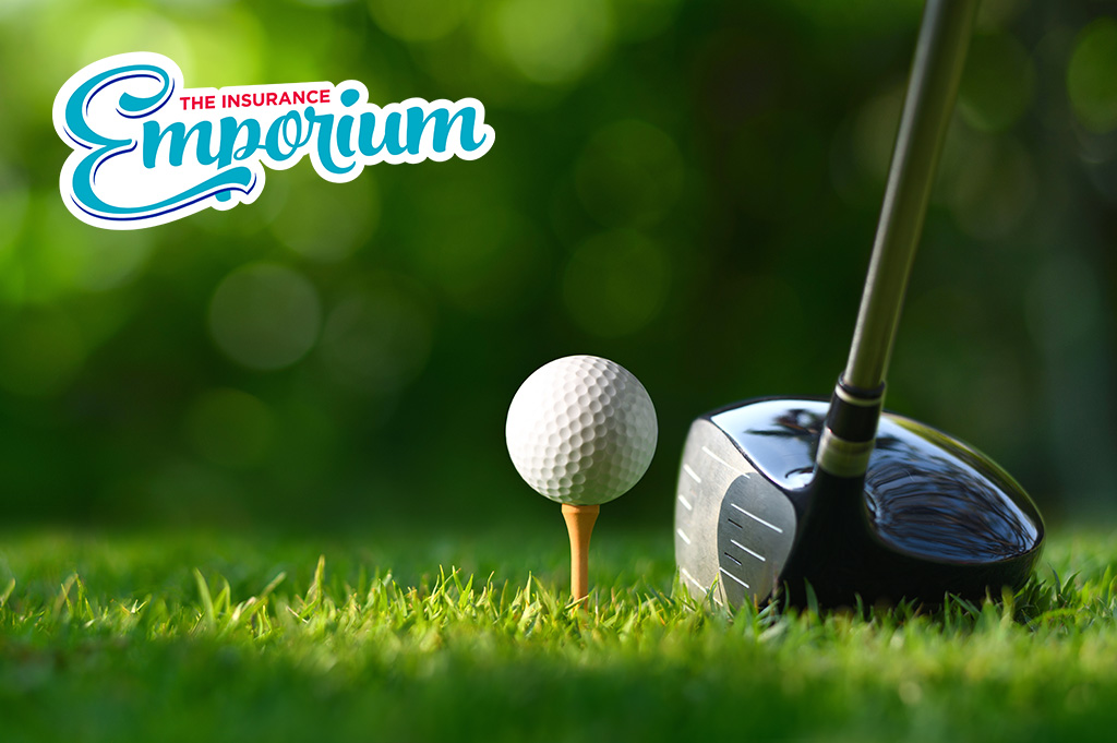 A close up shot of a driver golf club and a ball on top of a golf tee situated on a green.