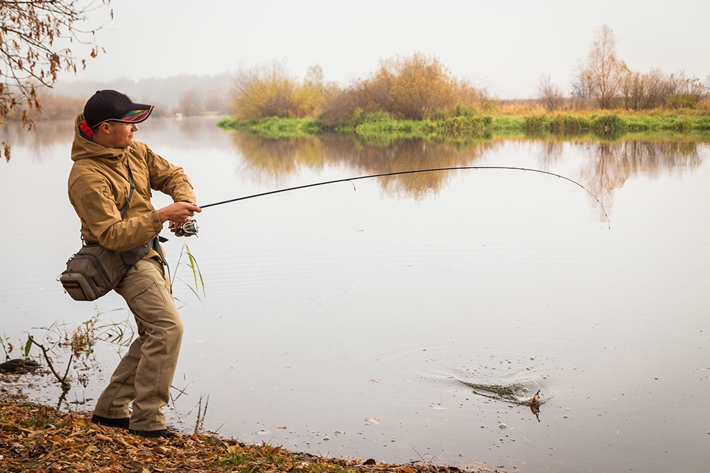 Fisherman on the autumn background. Fisherman in his hand holding spinning. Fishing, spinning reel, fish, Breg rivers. - The concept of a rural getaway. Article about fishing.